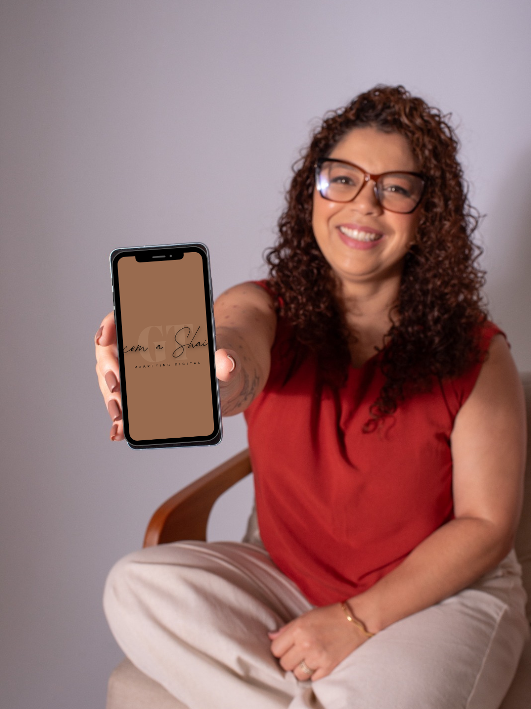 Shai sorrindo e apresentando um celular